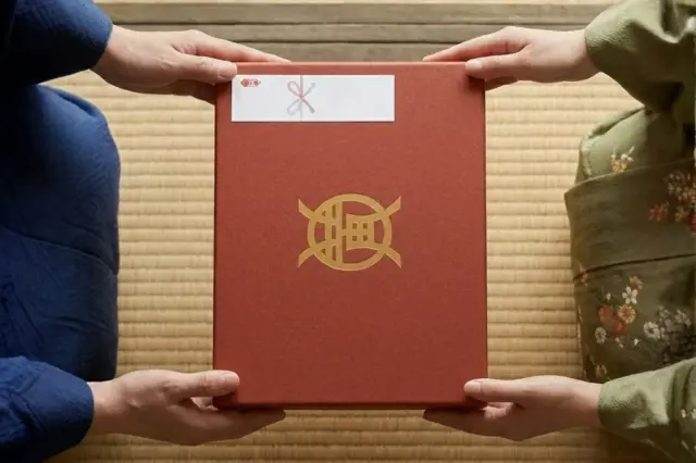 和牛である米沢牛の専門店、黄木の赤箱を畳の上で受け渡している画像