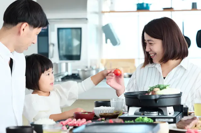 食卓を囲んで、家族が料理を楽しんでいる。和気あいあいとした画像。