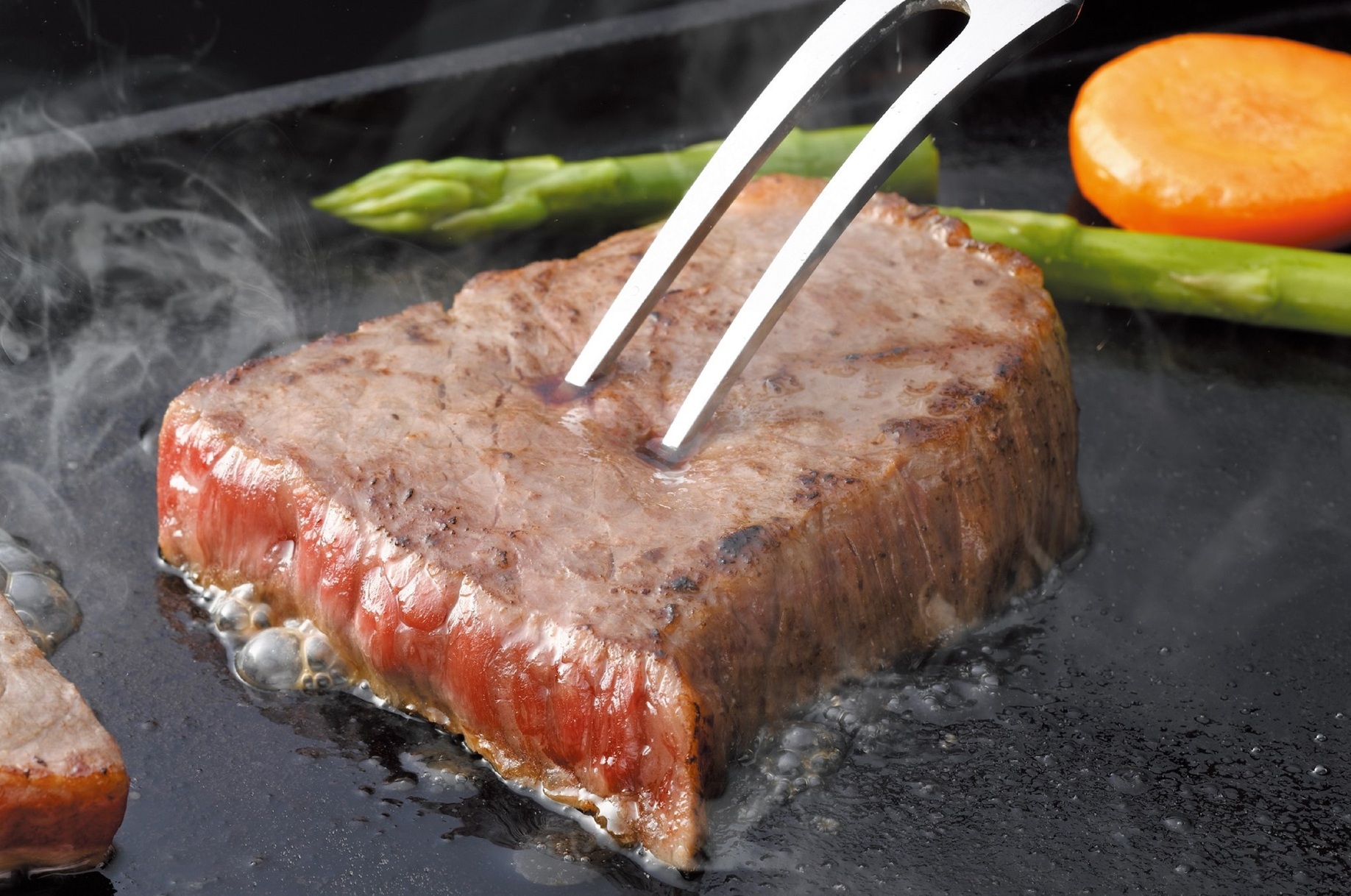 炭火の上で網に乗り、肉汁を溢れさせながら豪快に焼かれるBBQ塊ステーキ肉のイメージ